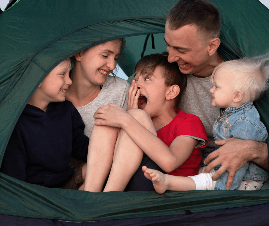 Perhe istuu teltan suuaukolla.