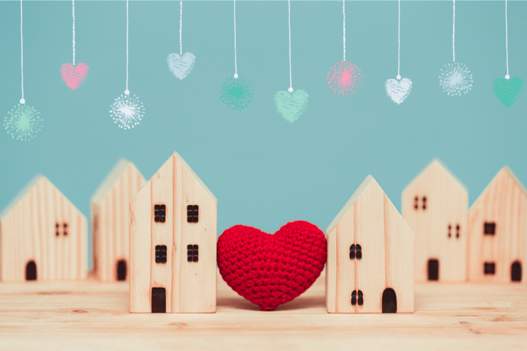 Kaksi taloa tai kotia, joiden välissä on sydän ja talojen päällä joulukoristeita.