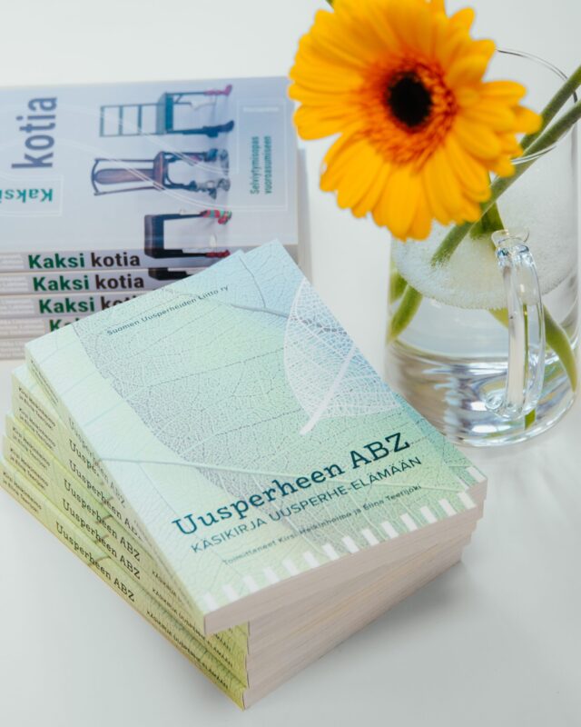 Kaksi kirjaa ja kukkamaljakko pöydällä.