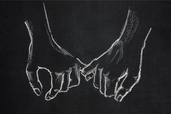 Liitutulululle piirretty kaksi kättä, jotka pitävät toisistaan kiinni.