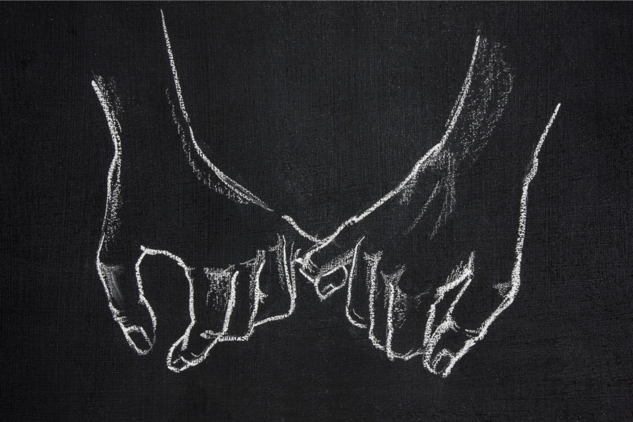 Liitutulululle piirretty kaksi kättä, jotka pitävät toisistaan kiinni.