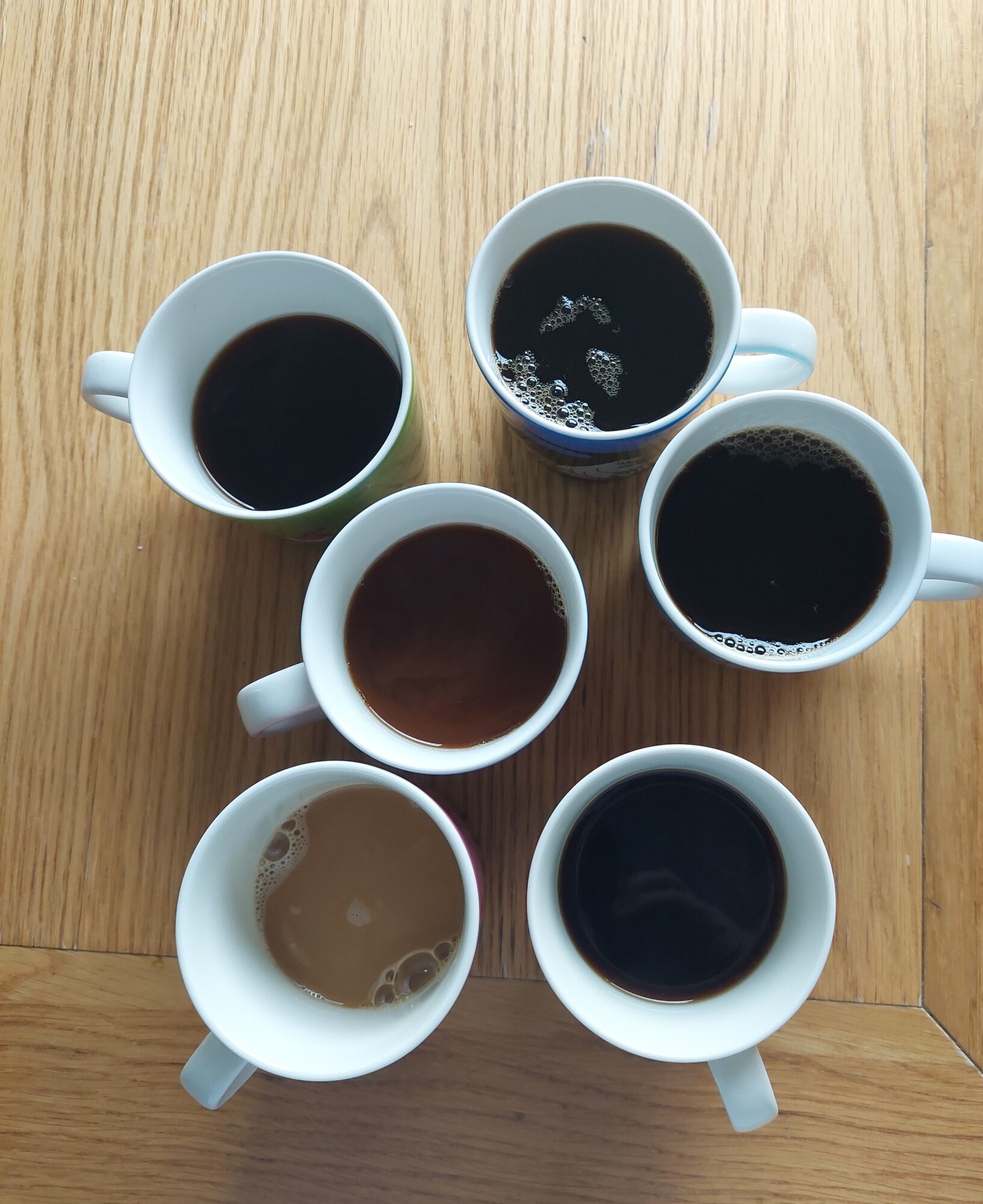 Kuusi kahvikuppia pöydällä.