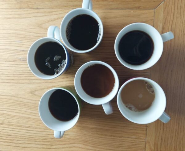 Kuusi kahvikuppia pöydällä.